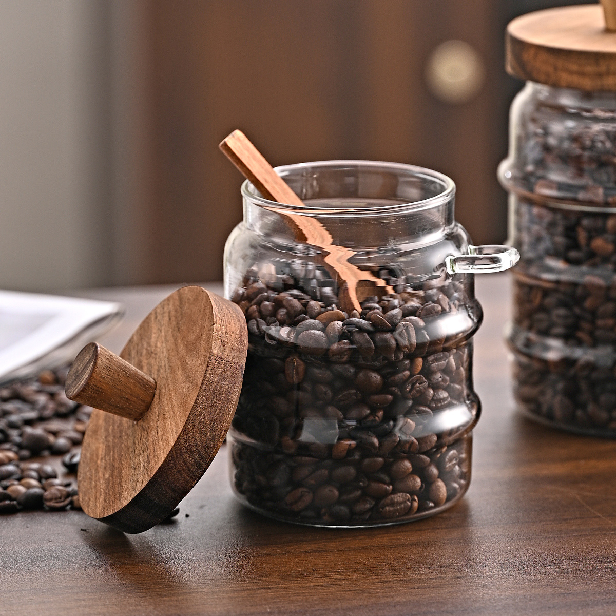 Open Glass Jar with Acacia Lid Off and Handcrafted Wooden Spoon Scooping Spices